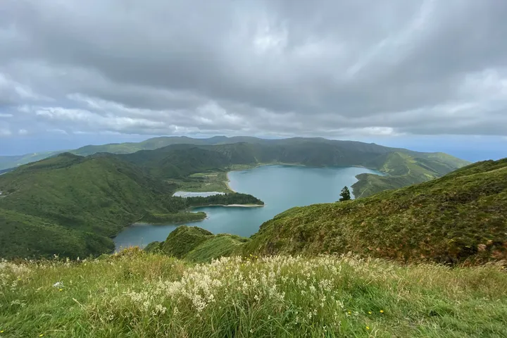 Lagoa do Fogo, a crater lake between green hills under a heavy sky.