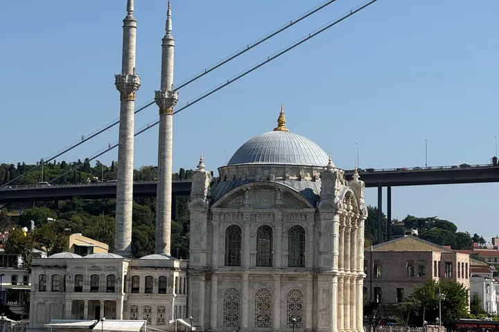 Ortaköy Mosque on the Bosphorus shore, with two slim minarets and the cables of a suspension bridge behind.