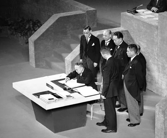 Prime minister Shigeru Yoshida signing the San Francisco Peace Treaty, watched by members of the Japanese delegation